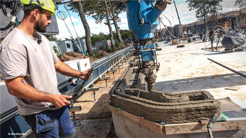 Operator overseeing the BOD2 3D construction printer during printing of concrete walls for the student housing project in Denmark.