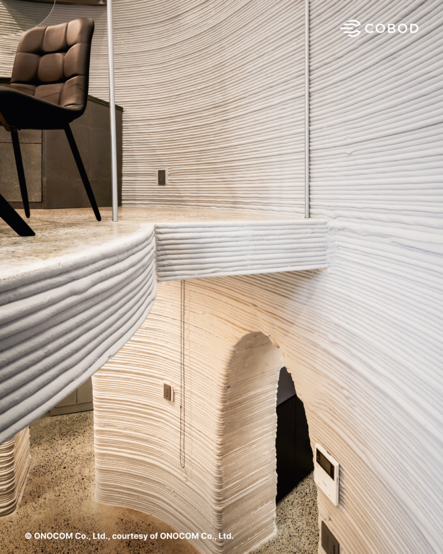 3D printed floor slab integrated into the structural and architectural design, reinforcing the continuous curved geometry throughout the building.