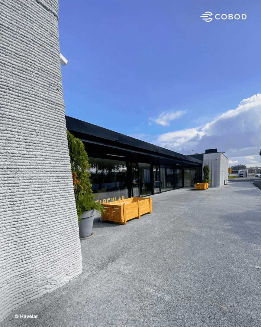 The completed recycling center office exterior. Curved 3D printed concrete columns frame the entrance facade.