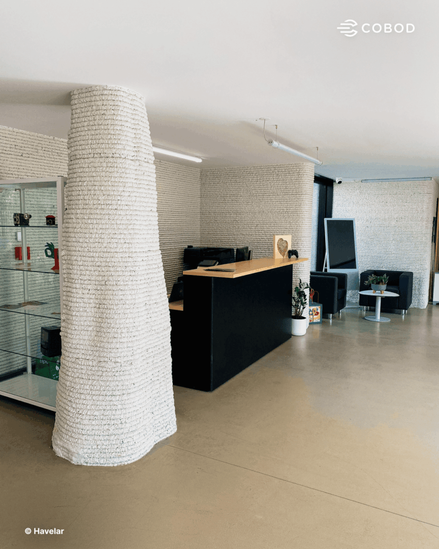 The reception area of the completed building. The tapered 3D printed concrete column illustrates the complex geometries achievable with construction 3D printing.